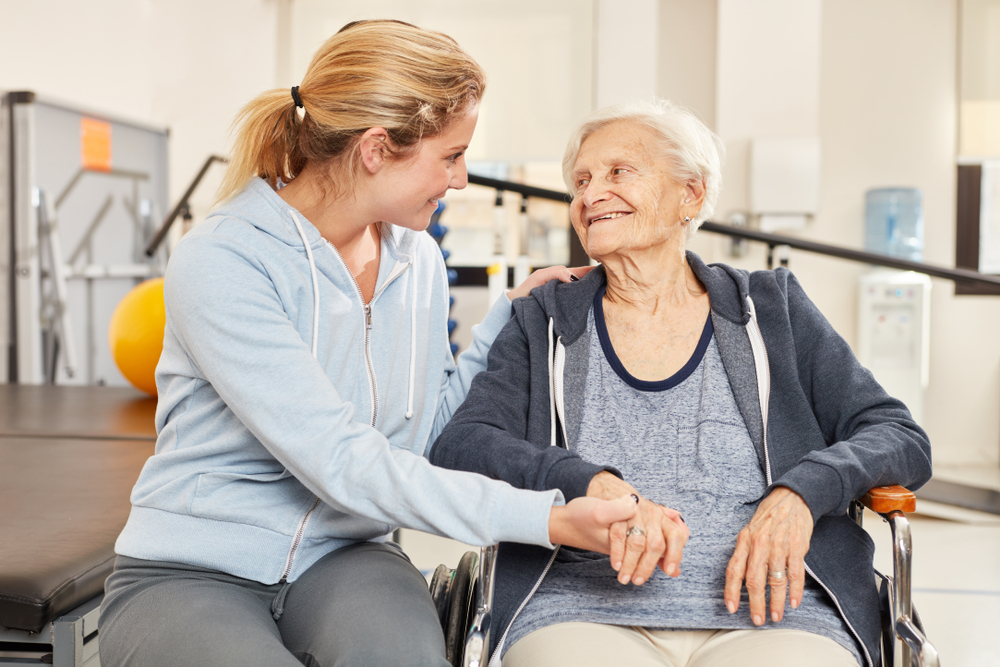 Oude patiënte toont dankbaarheid aan fysiotherapeute in het verpleegtehuis.