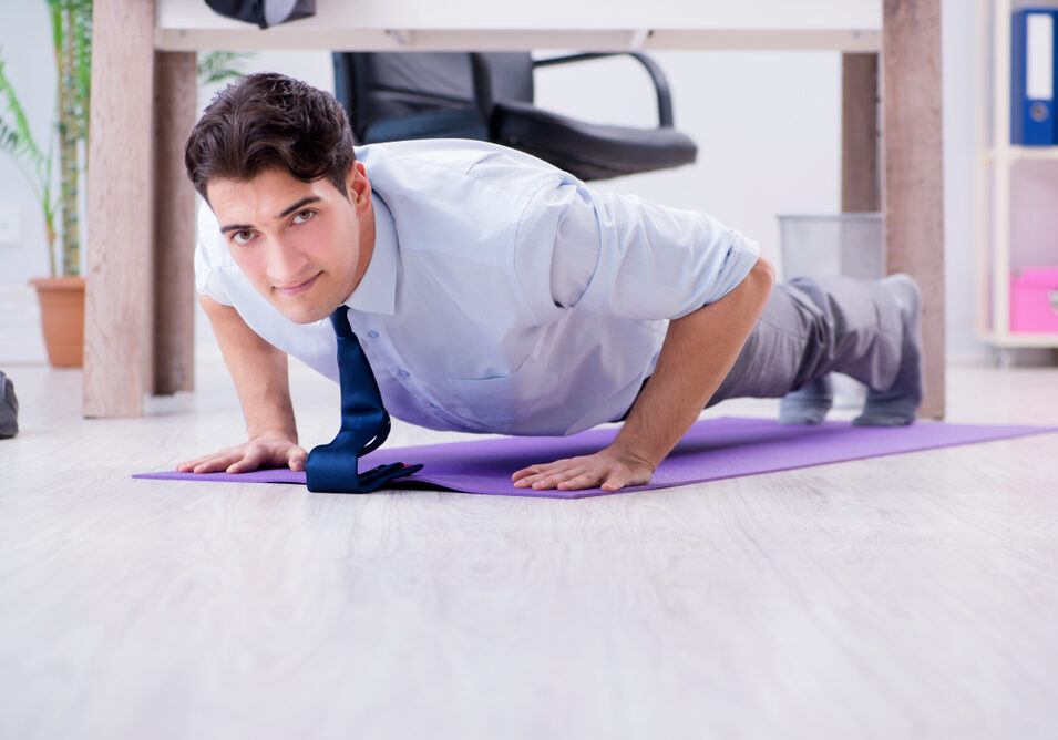 Man doet op zijn werk in de pauze push-ups en voorkomt daarmee rugklachten.