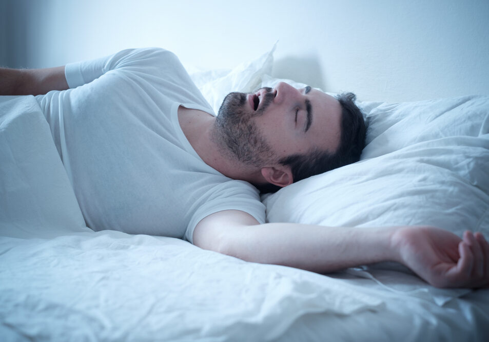 Man met slaapapneu in bed heeft baat bij ademoefeningen.