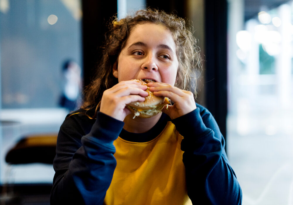 Adolescente eet hamburger.