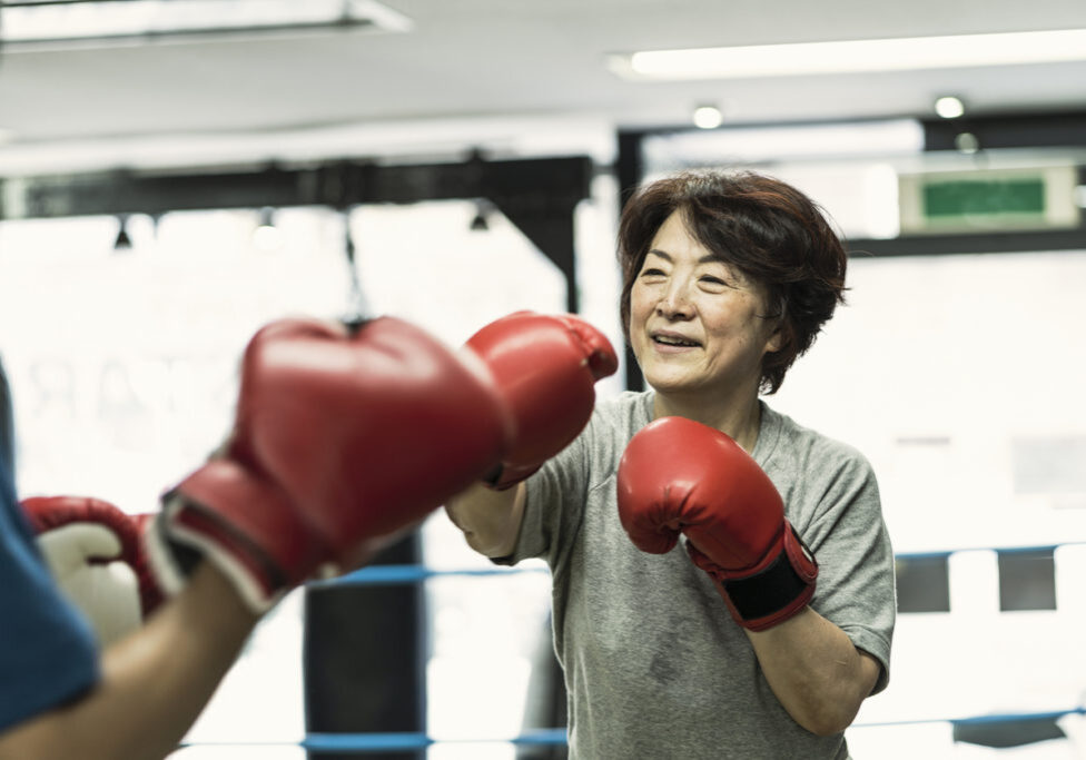 Japanese senior adult women training with male instructor at boxing gym