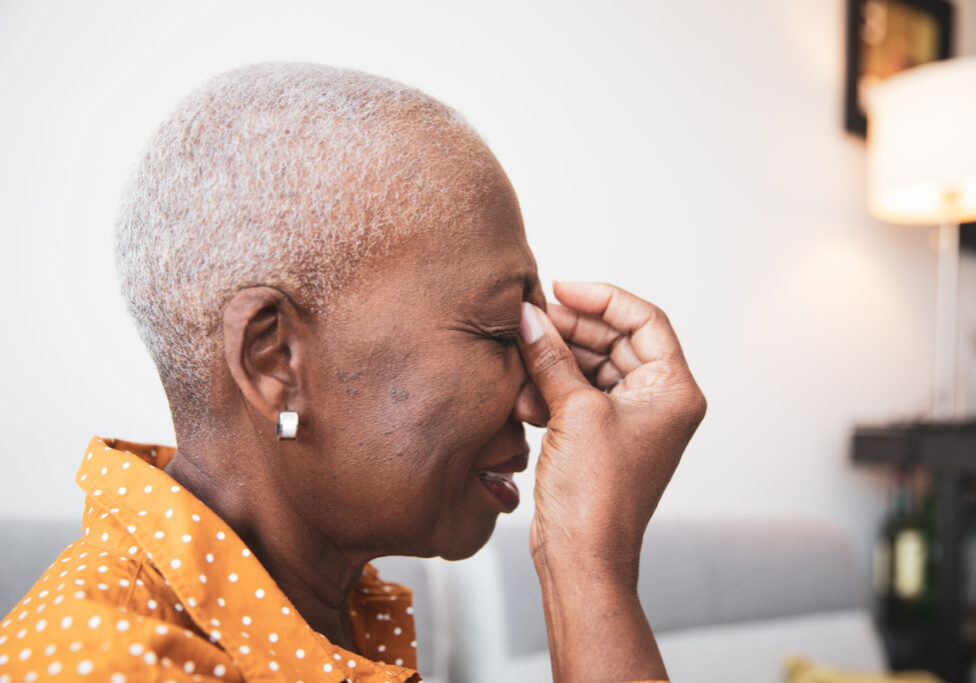 senior African descent woman holding her head in pain