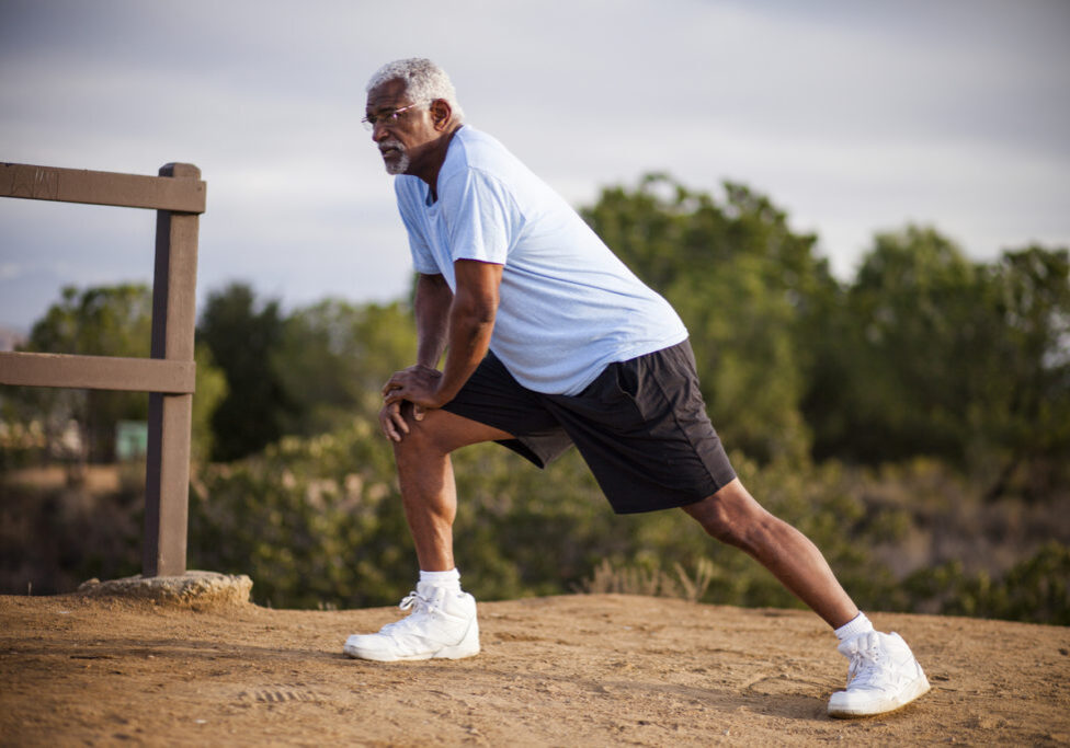 An attractive senior black man exercises outdoors with various muscle stretches