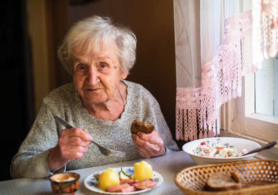 Elderly russian woman portrait dines in his home.