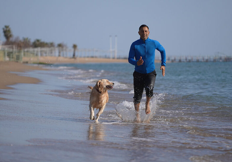 Man running on the beach with his dog